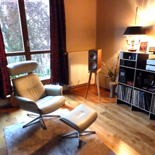 Load image into Gallery viewer, Music room with KEF R3 speakers on speaker stands with isolation plinth from Audio Chic. A white armchair, ottoman, and record player.