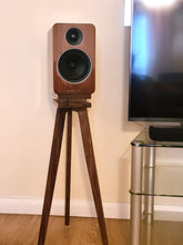 Load image into Gallery viewer, An acoustic energy AE1 wooden speaker sits on a Heron Speaker stand in walnut, with isolation plinths, next to a television in a room.
