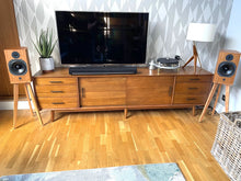 Load image into Gallery viewer, Wooden entertainment console with TV, speakers on ATC SCM11 speaker stands by audio chic, and record player against a patterned wall.