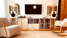 Load image into Gallery viewer, Living room with a television, speakers on audio chic speaker stands for the ATC scm11 speakers, and bookshelf filled with records.