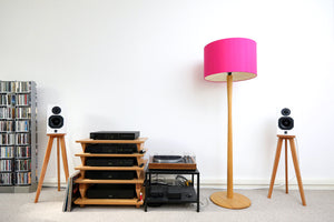 Home entertainment system with ATC SCM7 speakers on Audio chic speaker stands, CD player, and pink floor lamp against a white wall.