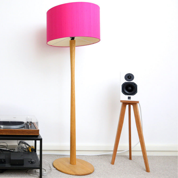 Floor lamp with pink shade and a ATC SCM7 speaker on a Heron wooden spaeker stand by audio chic against a white wall.