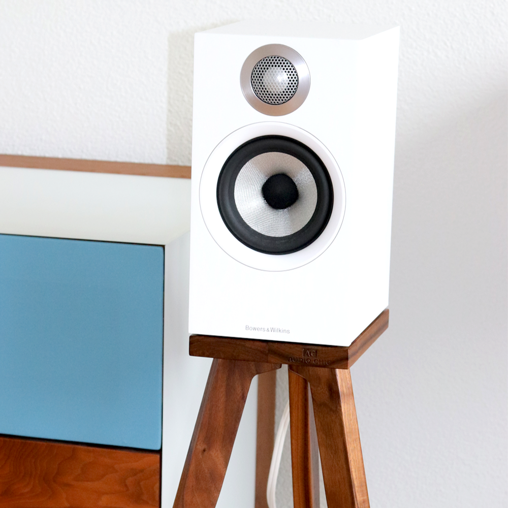 B&W 607, 607 S2 and 607 S3 speaker stands in walnut in a living room. White speaker on a wooden stand against a white wall