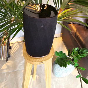 B-and-W-Formation-Flex-Egret-speaker-stand-in-Walnut-by-audio-chic against a plant and sofa