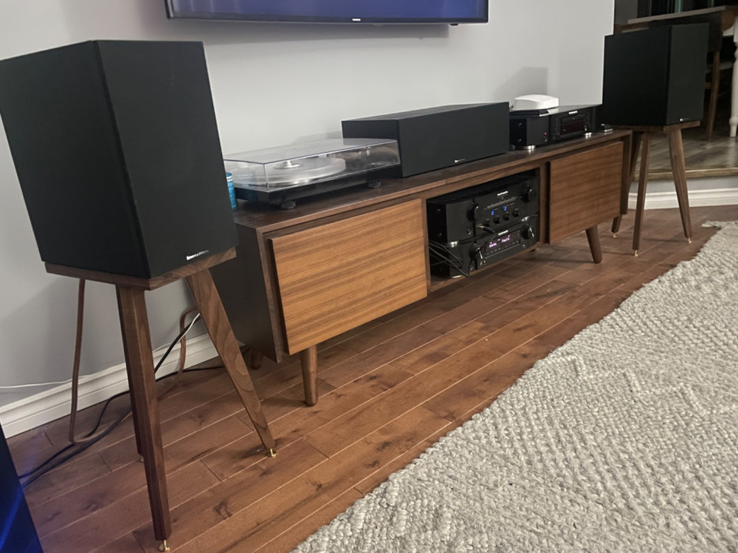 A pair of B&W 606 speaker stands in a room, with speaker spikes and shoes, finished with a hard wax finish.