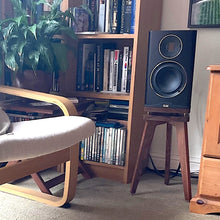 Load image into Gallery viewer, Elac Carina Speaker on a Walnut Audio Chic speaker stand in a room setting next to a bookcase and comfy chair