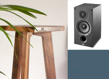 Load image into Gallery viewer, An Elac Debut B5.2 speaker with a wooden stand with a tripod base, with a plant in the background and Audio Chic brand logo on the front