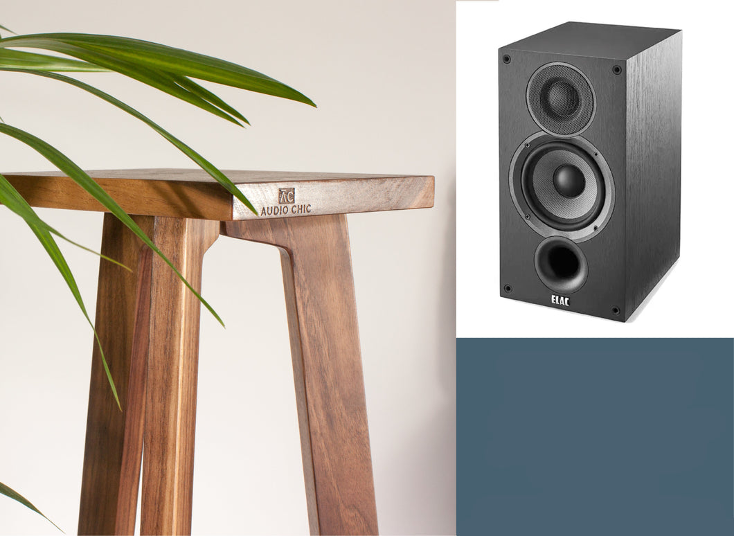An Elac Debut B5.2 speaker with a wooden stand with a tripod base, with a plant in the background and Audio Chic brand logo on the front