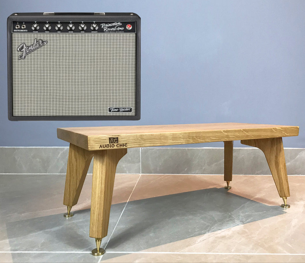 Wooden centre speaker with 'Audio Chic' branding next to a Fender amplifier against a blue wall.