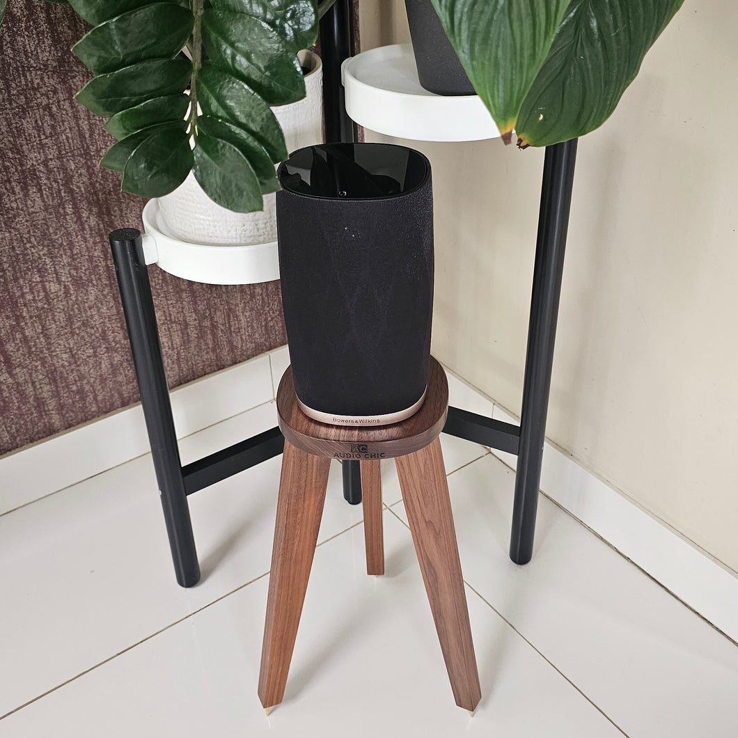 Formation Flex speaker stand in Walnut with the Audio Chic brand logo on the front, set next to a plant stand.