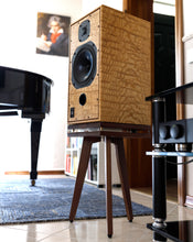 Load image into Gallery viewer, Wooden Harbeth C7ES3 speaker with walnut speaker stand with an isolation plinth from Audio Chic in a room with a piano and mirror.