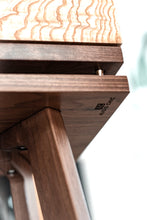 Load image into Gallery viewer, Underside of walnut speaker stand with the Audio Chic logo branding on the underside. The stand also shows an isolation plinth.