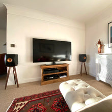 Load image into Gallery viewer, Living room with a TV, speakers, and a couch and KEF-LS50-walnut-heron-speaker-stand-by-audio-chic