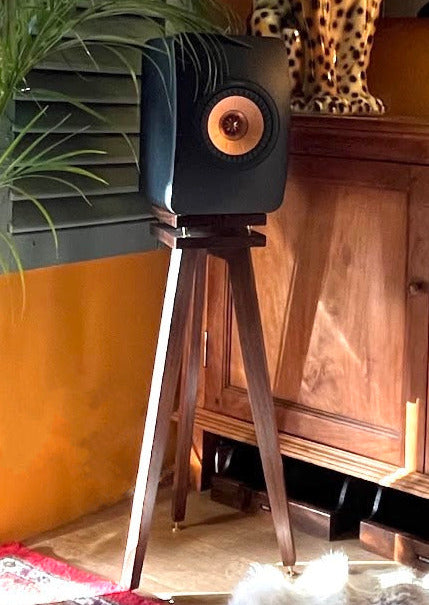 KEF Ls50 meta speaker on a wooden speaker stand by Audio Chic in a corner of a room.