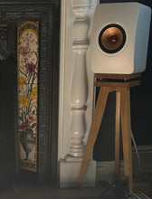 Load image into Gallery viewer, A pair of KEF LS50 Meta speaker stands in maple wood finish, with a speaker positioned on the stand in front of a decorative fireplace.