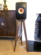 Load image into Gallery viewer, KEF-LS50-Meta-walnut-heron-speaker-stand-by-audio-chic in a room with a stone wall and wooden cabinet.