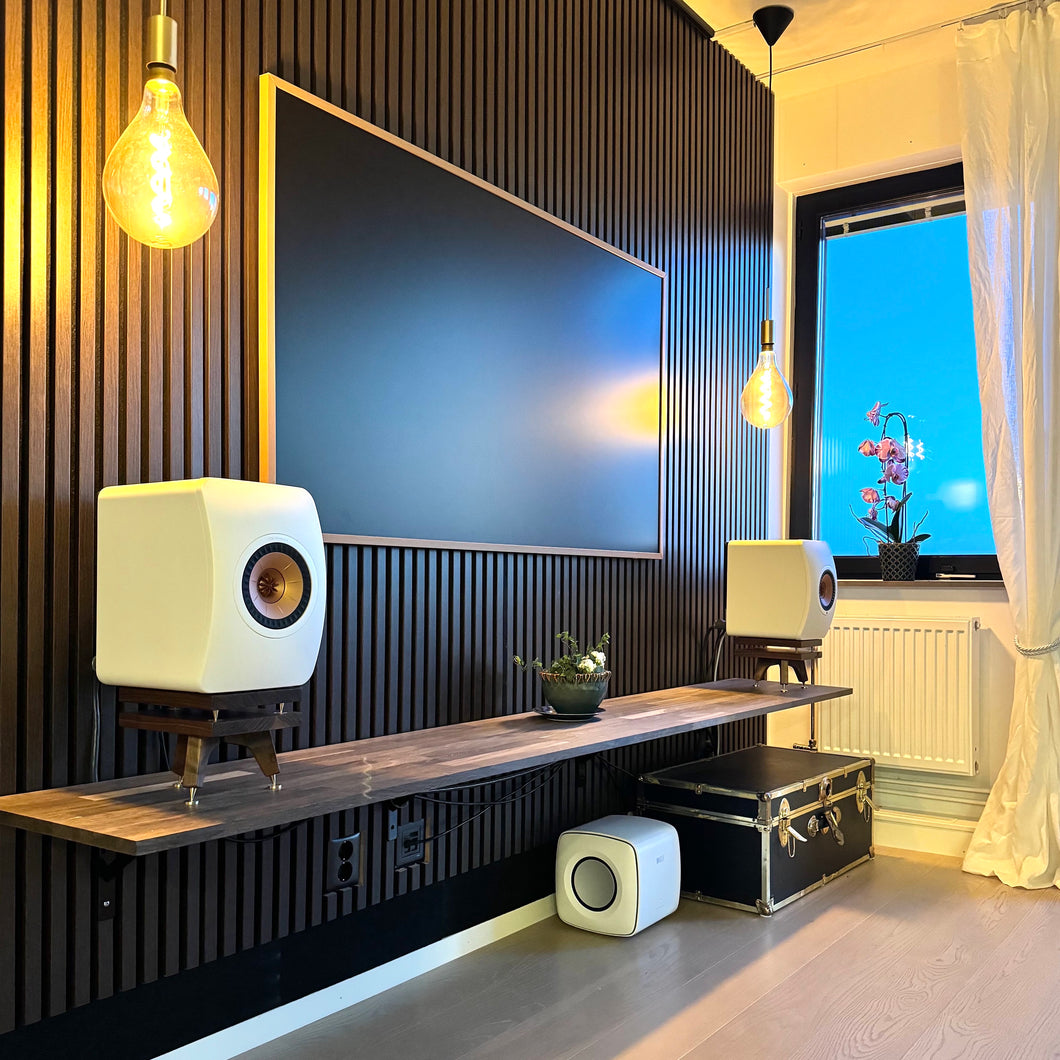 Modern living room with a large TV, KEF-LS50-Metas-snipe-speaker-stands-in-Walnut-with-Plinths-by-audio-chic, and decorative elements.