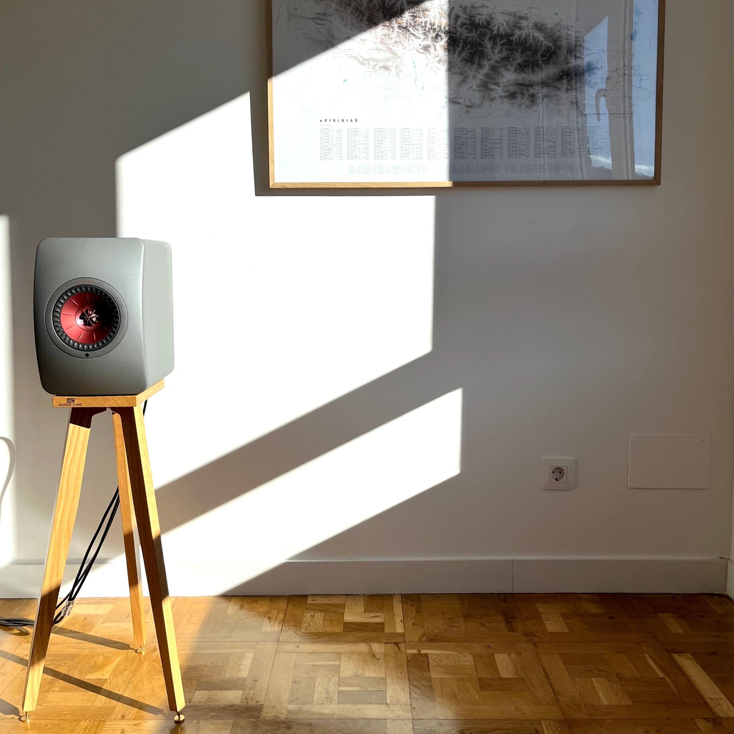 KEF-LS50-Wireless-650-Oak-speaker-stands-by-audio-chic in a room with a framed picture on the wall