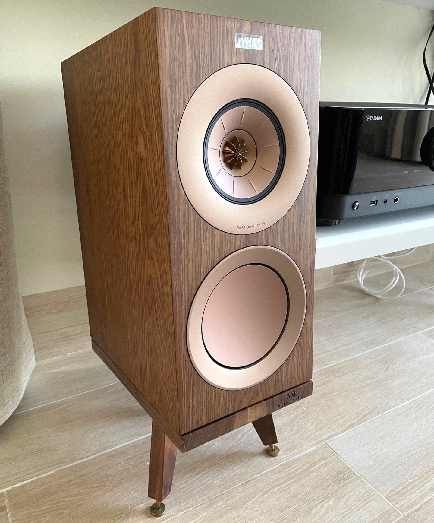 Wooden KEF R3 speaker on a Snipe speaker stand by Audio Chic on a light wooden floor.