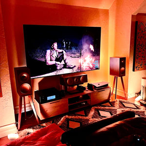 Living room setup with a TV, KEF R3 speakers on Walnut speaker stands by Audio Chic, and a cosy atmosphere.