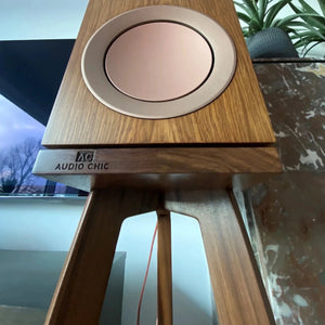 Wooden KEF R3 speaker on a walnut speaker stand, close up with 'Audio Chic' branding.