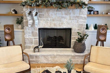 Load image into Gallery viewer, Living room with KEF R3 speakers on Walnut audio chic speaker stands, stone fireplace, beige chairs, and a glass coffee table.