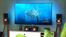 Load image into Gallery viewer, Klipsch-RP500M-II-Walnut-with-plinths-speaker-stands-by-audio-chic. TV screen displaying a turtle image with speakers on either side in a room.