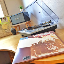 Load image into Gallery viewer, Record player with a vinyl record on a wooden table with a Marshall Stanmore speaker on a centre speaker stand by audio chic.