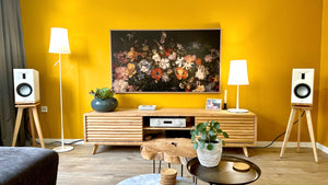 Living room with yellow walls, a TV, Martin-Logan-Motion-XT-B100-Oak-600-speaker-stand-by-audio-chic, and decorative items.