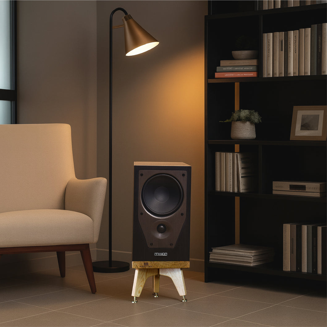 Mission M72 Speaker on a Snipe Speaker stand by Audio Chic in a room with a chair, floor lamp, and bookshelf.