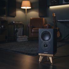 Load image into Gallery viewer, Mission_LX_1_MKII_on_the__Snipe_Speaker_stand_in_oak_by_audio_chic in a dimly lit music room with a lamp and chair.