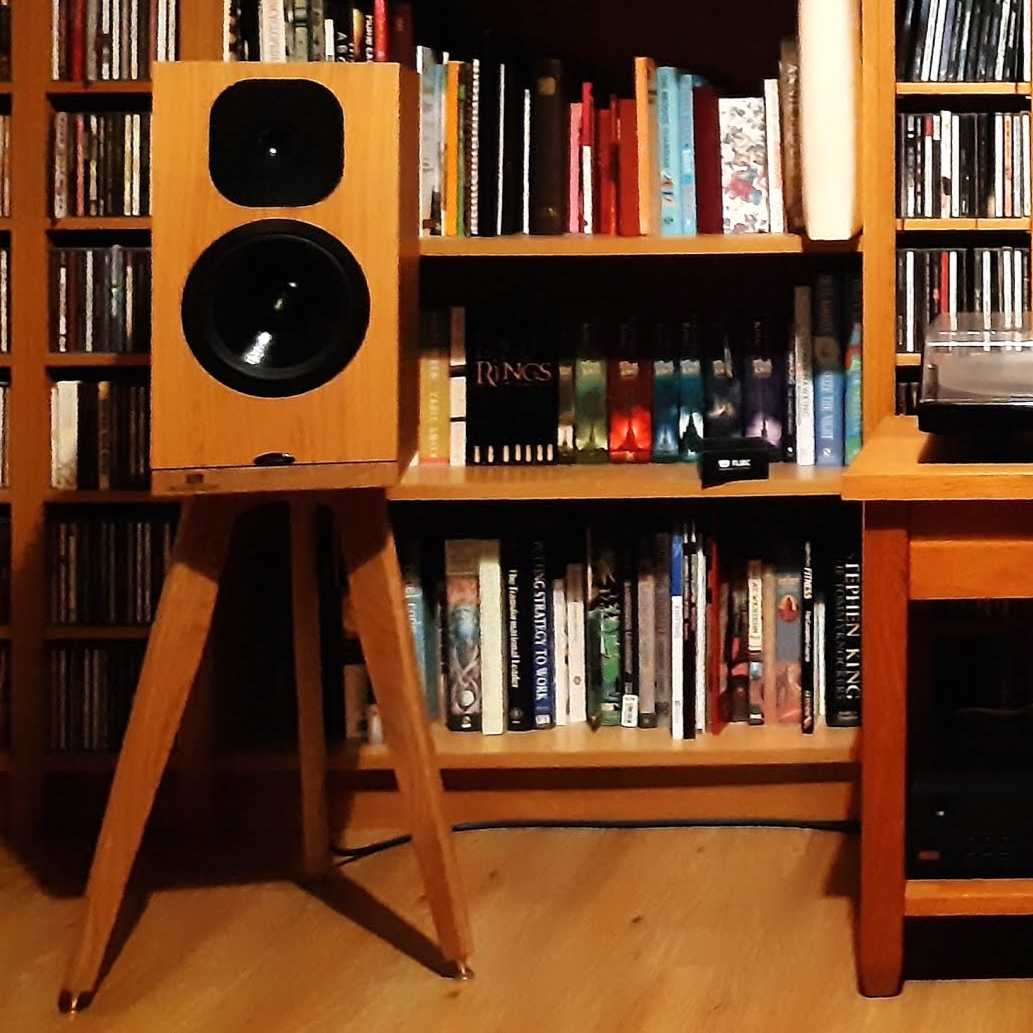 Wooden bookshelf with books and Neat-Momentum-SX3i-Egret-speaker-stand-audio-chic in a room setting.