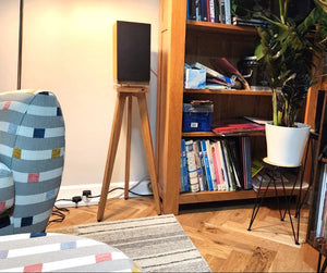 Pro-ject-speaker-box-5-S2-The-Heron-700-Oak-with-Plinths-from-audio-chic in a Living room with a colourful armchair, bookshelf, and record player.