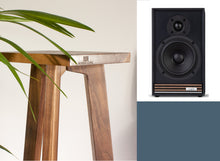 Load image into Gallery viewer, A pair of Ruark Sabre-R speaker stands with a range of heights from 140-900mm, positioned next to a plant.
