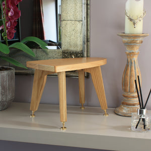 Wooden stool on a shelf with decorative items including a candle and diffuser.