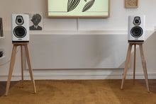 Load image into Gallery viewer, Sonus-Faber-Sonetto-I-Heron-shaped-speaker-stands-by-audio-chic in a modern room setting with a stricking modern picture in the background.