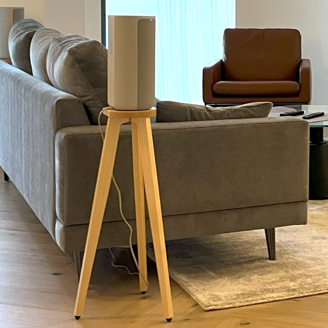 Modern living room with gray sofa, brown armchair, and wooden side table and a Sony hT-A9 speaker on a wooden speaker stand by audio chic