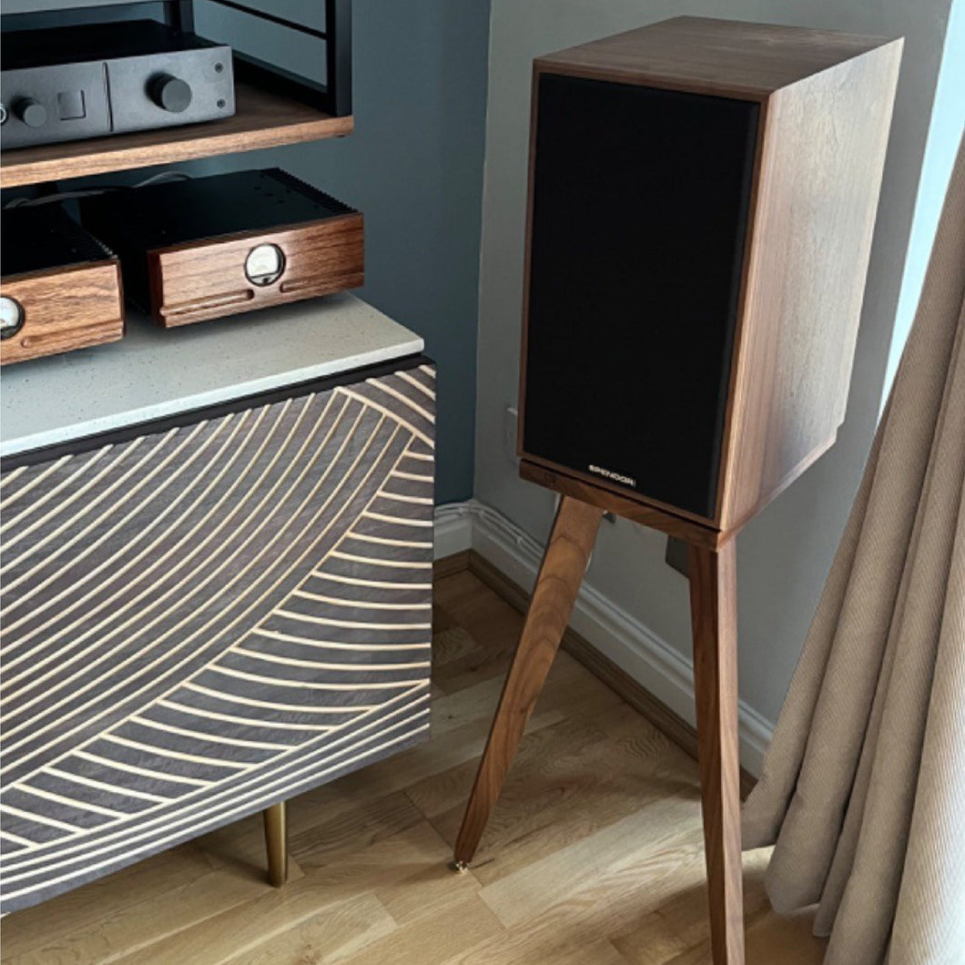 A Spendor Classic 3/1 speaker stand in a walnut finish, shown in two different positions, one as a floor stand, with a range of heights shown from 140-900mm. The stand is placed in a home environment with a pair of speakers on it.