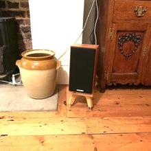 Load image into Gallery viewer, Spendor-S3-5r2-drunken-snipes-speaker-stand-in-oak-by-audio-chic next to an antique cupboard and a stove fireplace.