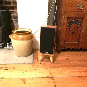Spendor-S3-5r2-drunken-snipes-speaker-stand-in-oak-by-audio-chic next to an antique cupboard and a stove fireplace.