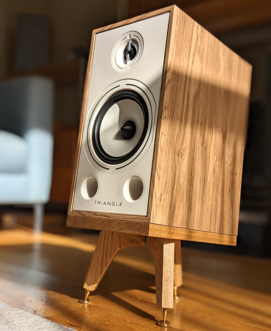 Triangle-Borea-BR03-drunken-snipe-speaker-stand-in-oak-by-audio-chic in a stylish room setting.