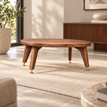 Load image into Gallery viewer, An Oval speaker stand for the Omnia speaker with angled legs and brass-spikes and disc feet, styled in a modern living room setting on a textured rug.