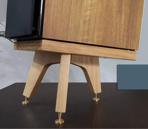 A pair of desktop speaker stands made of wood, with brass speaker spikes, placed on a desk.