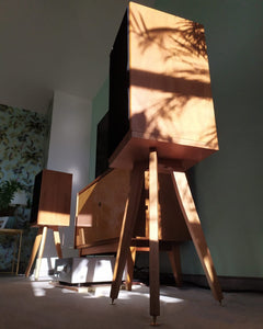 Harbeth C7ES3 Speakers Perfectly Seated on Cherry wood speaker stands in a living room next to a sideboard and tv.